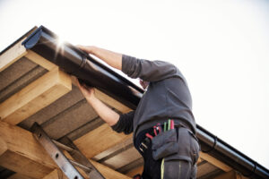 man on ladder installing gutters